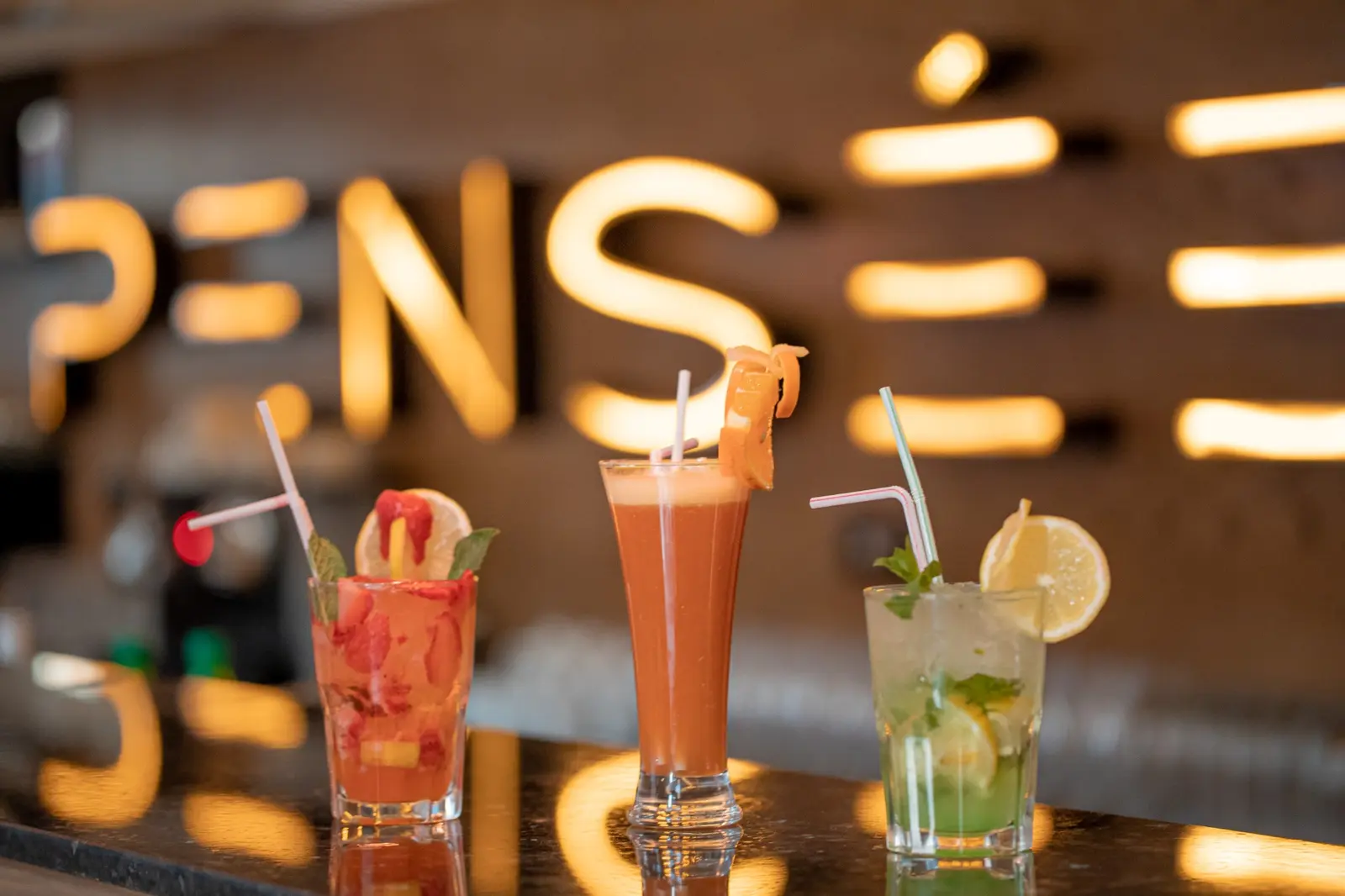 Three drinks at the bar, in front of the Pensée sign in Marrakech